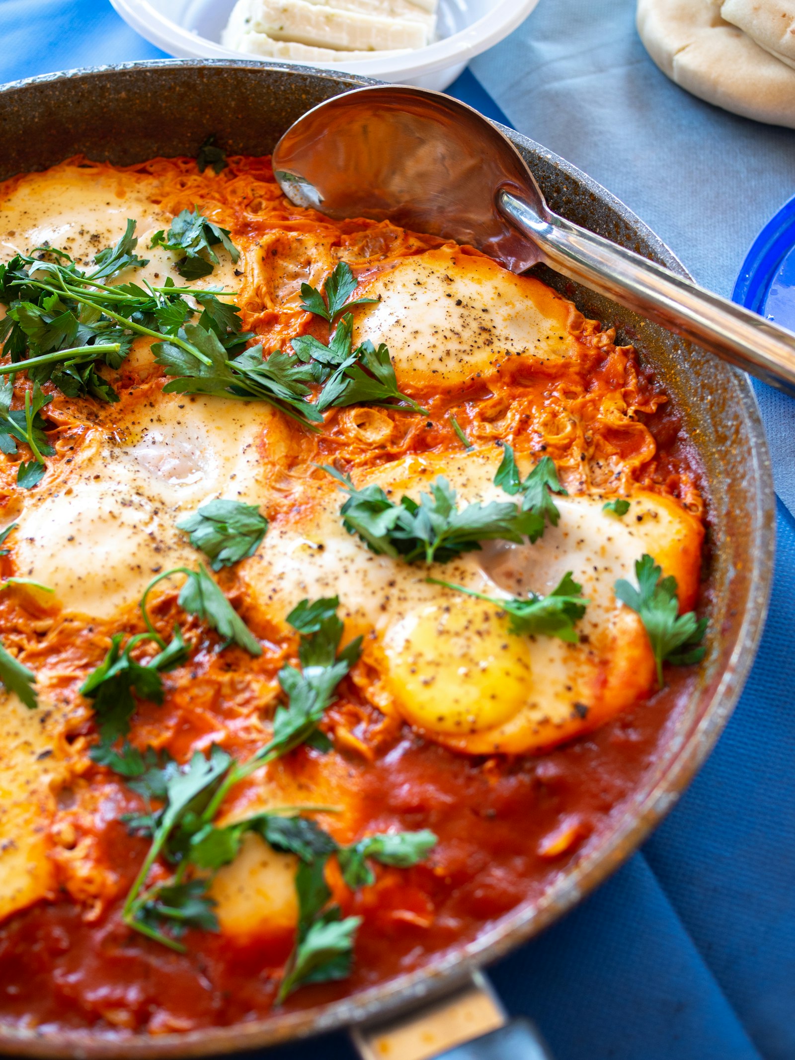 Skillet of shakshuka with poached eggs in spiced tomato sauce and parsley